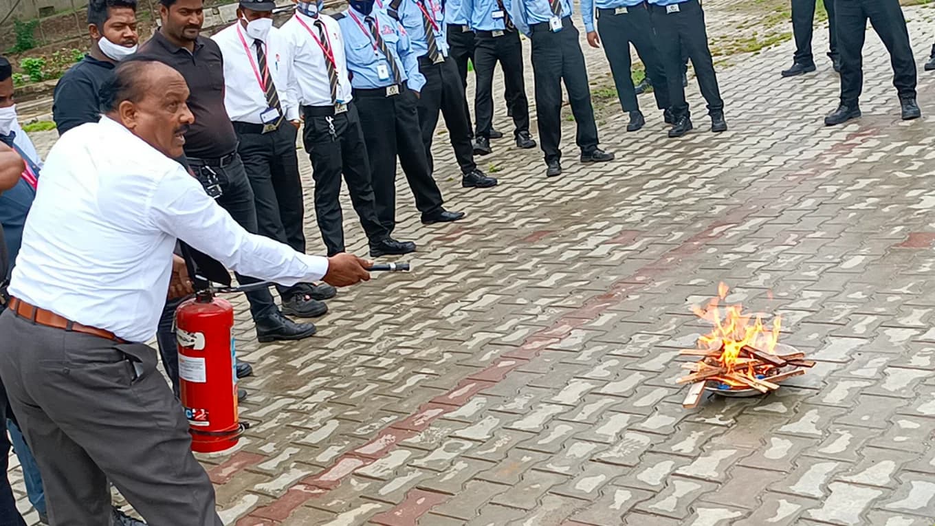 Trainer demonstrating fire extinguisher use on a live flame
